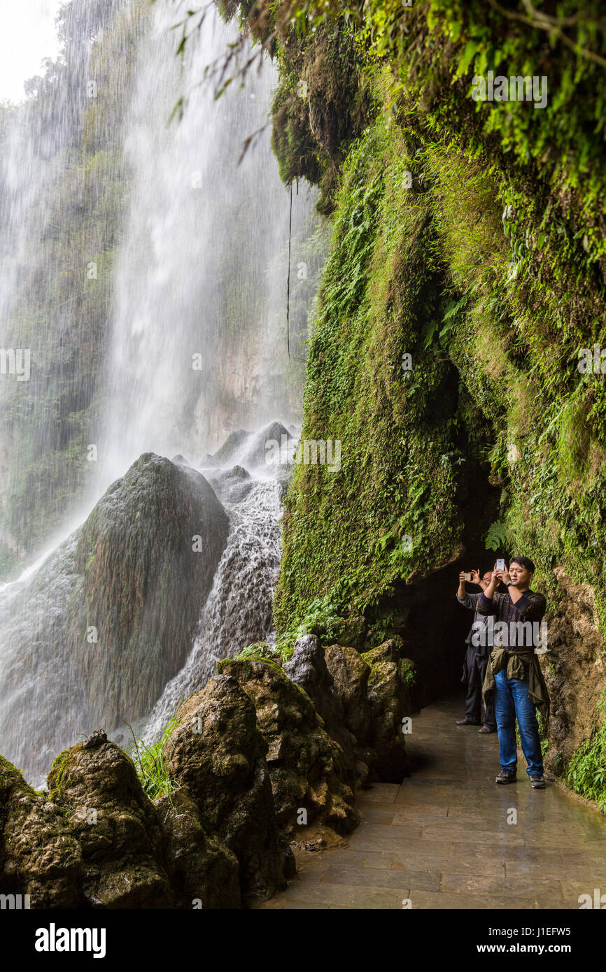 Guizhou Province, China.  Yellow Fruit Tree (Huangguoshu) Waterfall.  Tourists Taking Photos from behind the Falls. Stock Photo