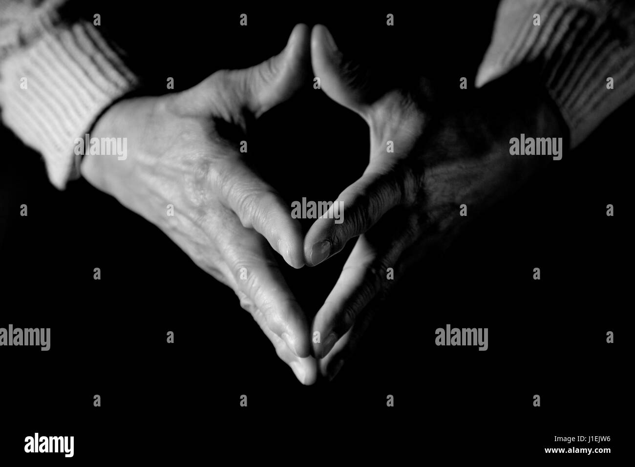 A black and white shot of a senior man clasped hands Stock Photo