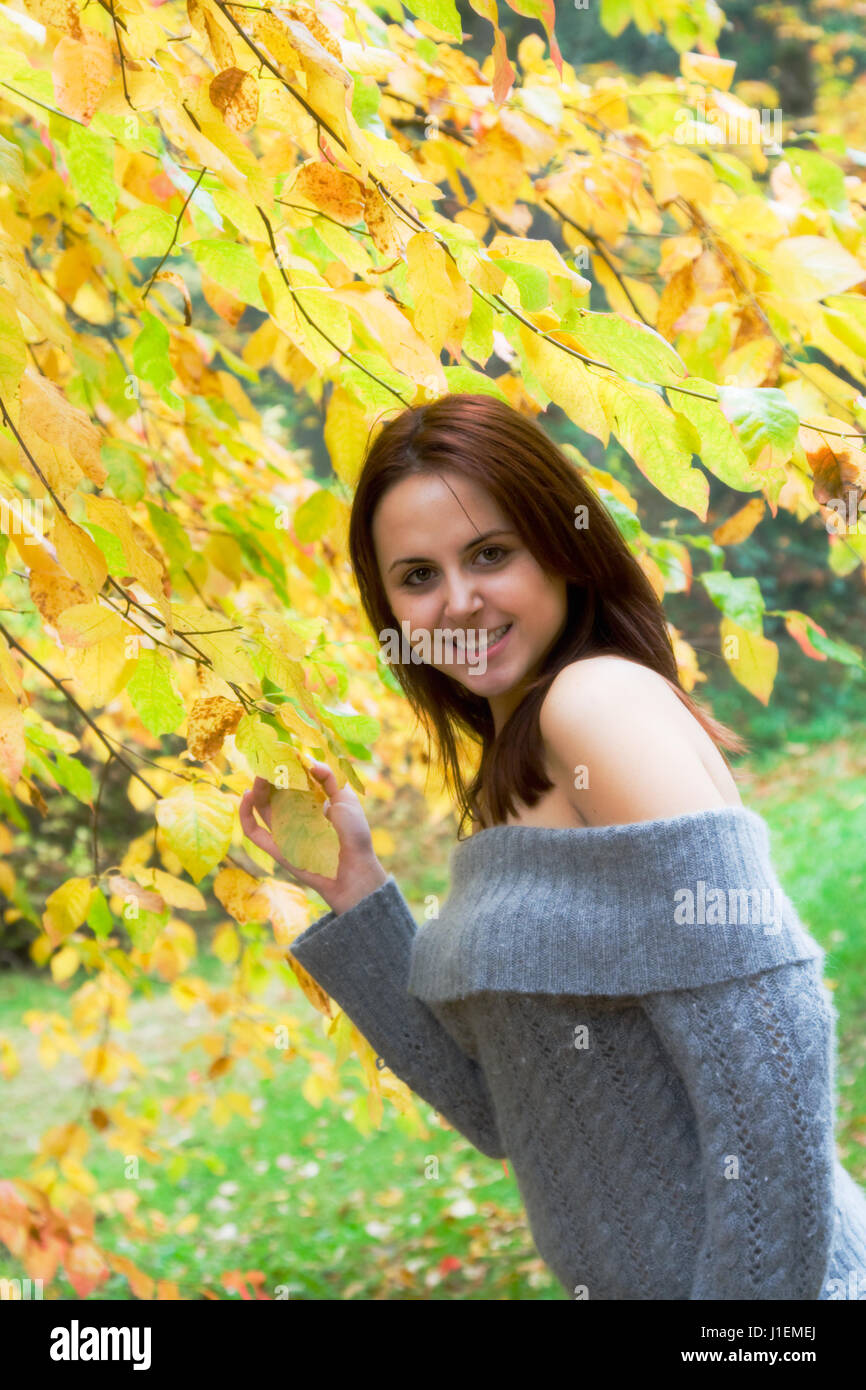 A portrait of a beautiful young caucasian girl holding yellow leaves in ...