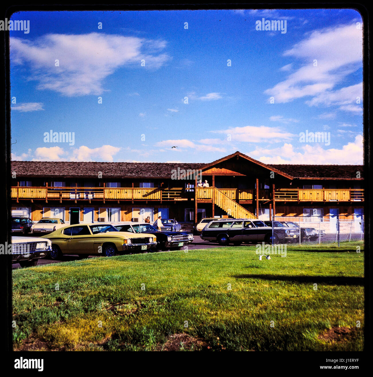 Slide 35 mm to photo. Old vintage vacation shot from 1960's showing hotel and vintage cars in the parking lot on a clear blue sky. Stock Photo