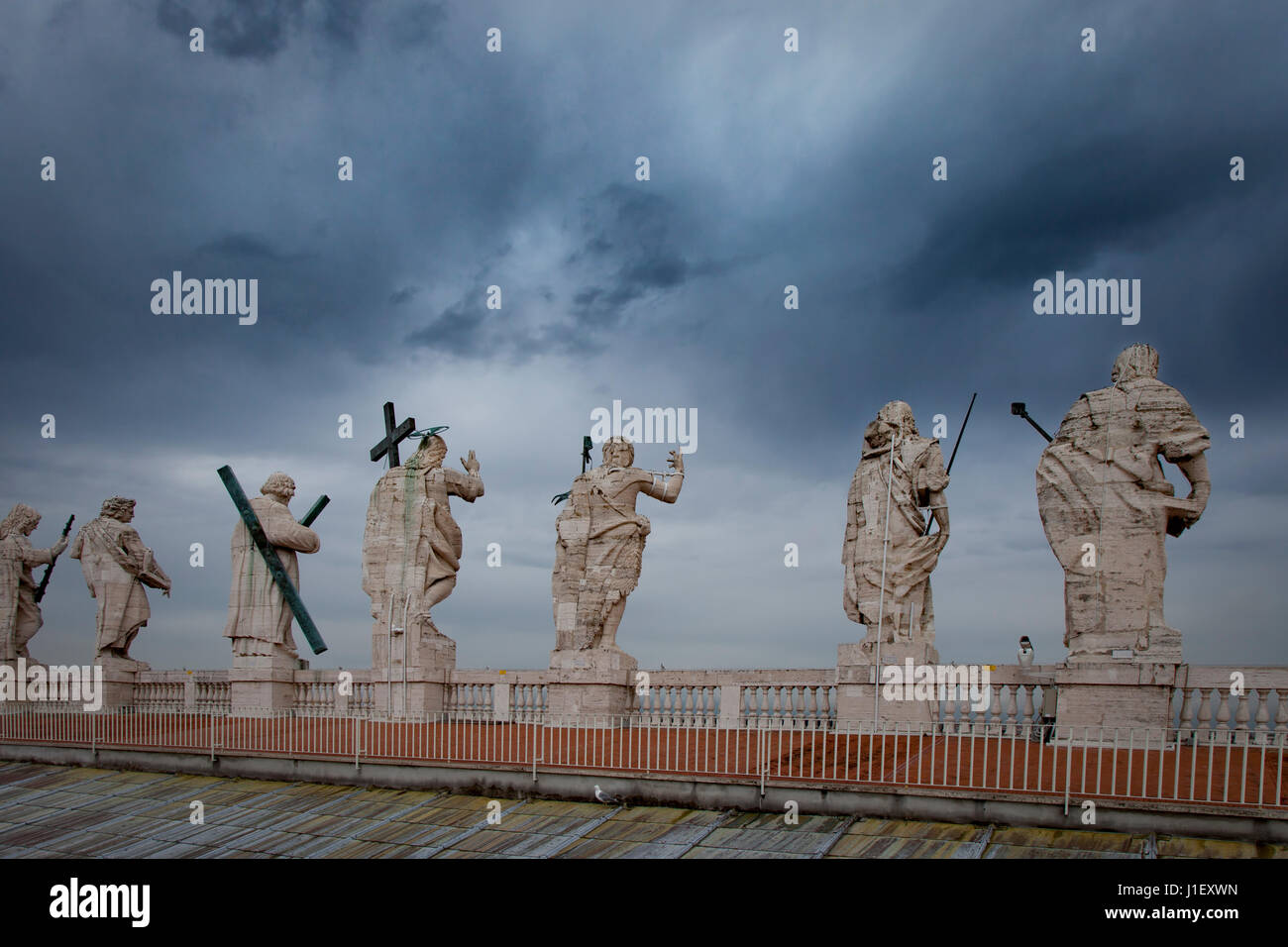 Stormy skies over the statues along the roof-line of Saint Peters Basilica, Vatican, Rome, Italy Stock Photo