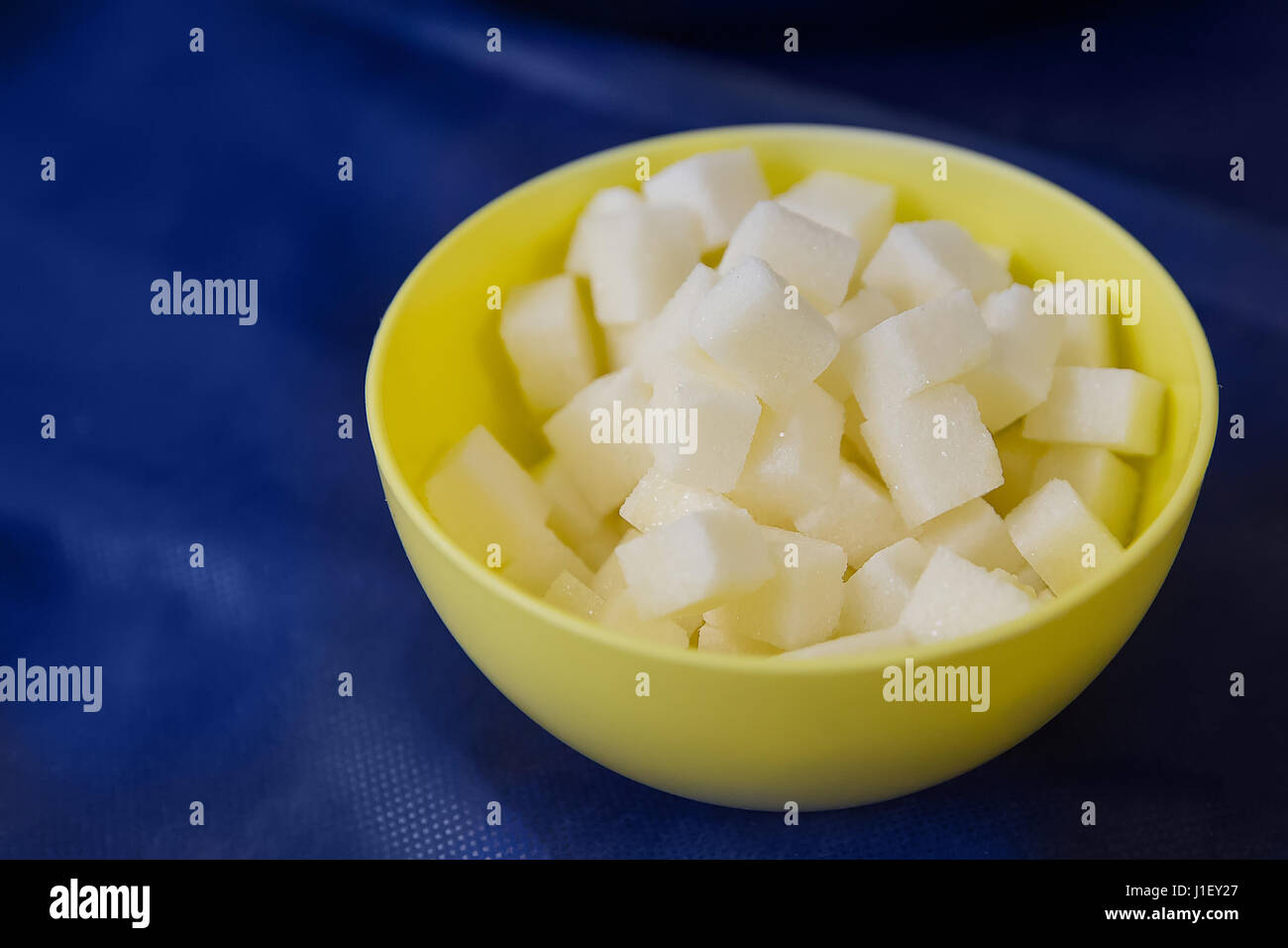 Sugar refined cubes in a yellow plate on a blue table Stock Photo