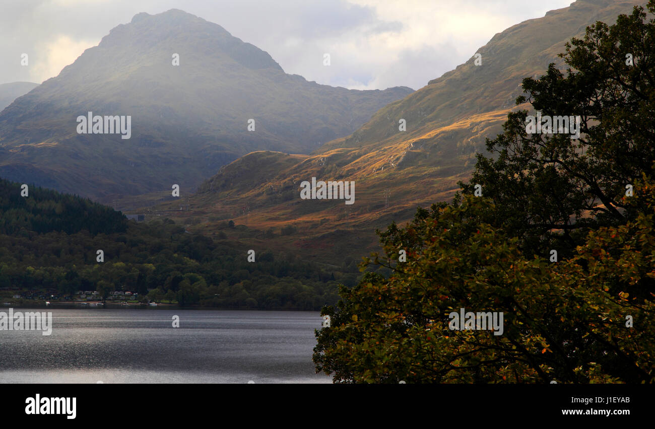 Ben Vane towers over Inveruglas and Loch Lomond as sunlight catches the flank of Ben Vorlich,   Arrochar Alps, Trossachs National Park, Scotland, Eur Stock Photo