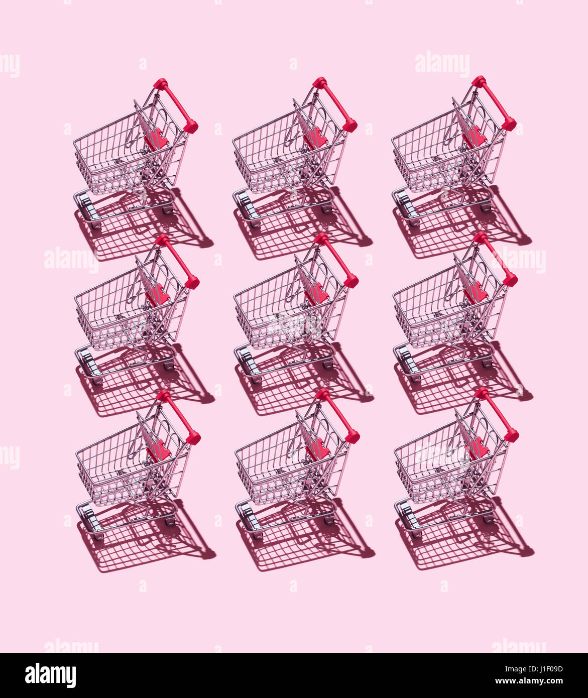 Multiple Shopping Carts organized over pink background Stock Photo