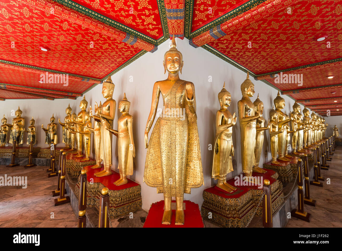A lot of golden Buddha statues under a decorated and red roof at the Wat Pho (Po) temple complex in Bangkok, Thailand. Stock Photo
