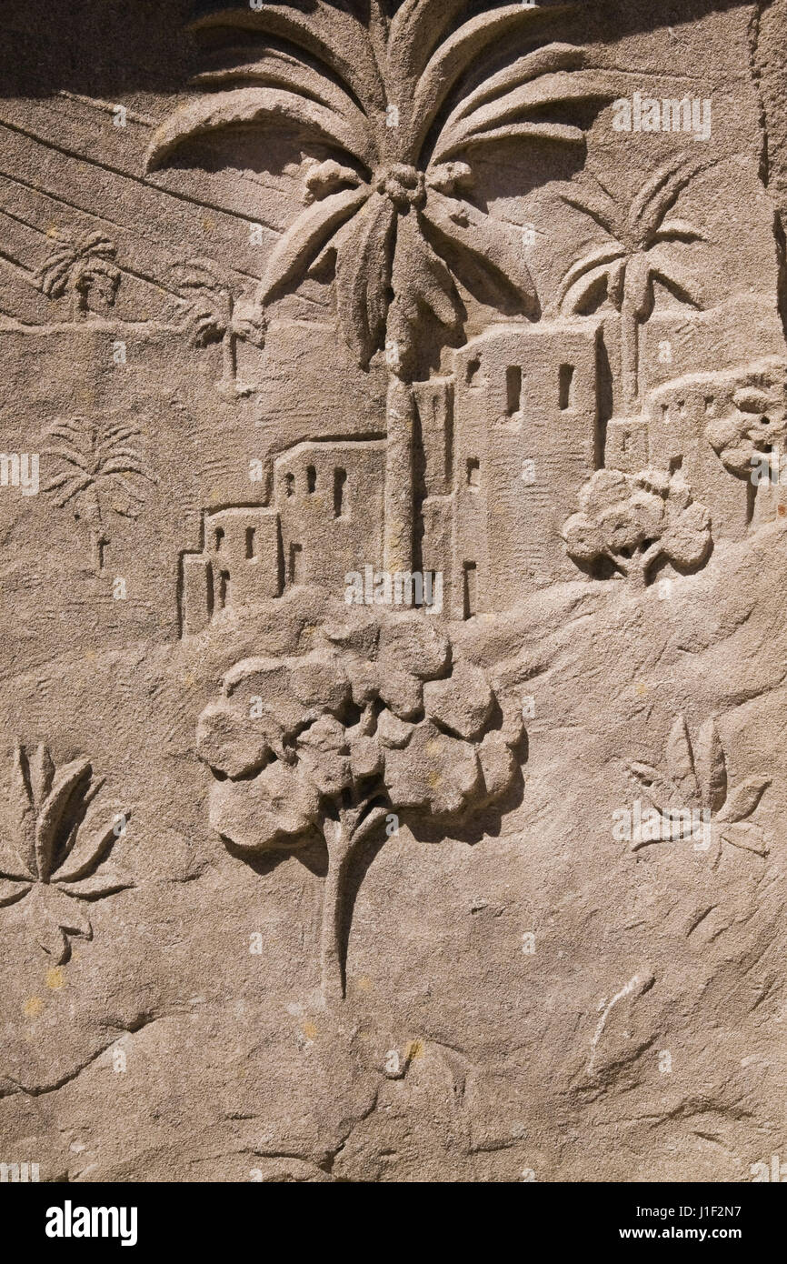 Stone carving of Arab architectural buildings and palm trees on a