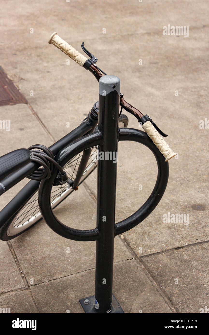 Old Bicycle chained to pole with ring Stock Photo