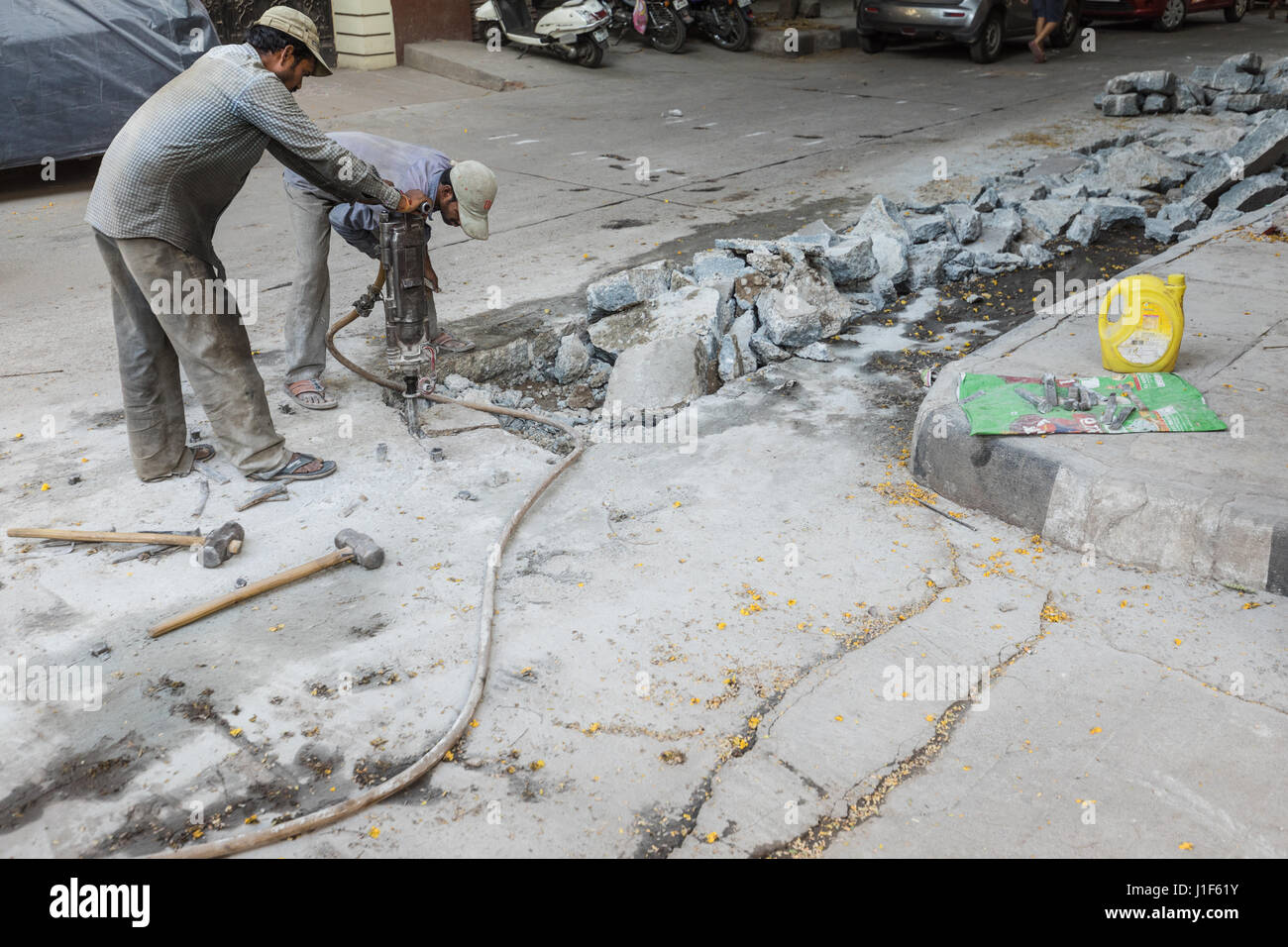 Worker using pneumatic hammer on city pavement Stock Photo