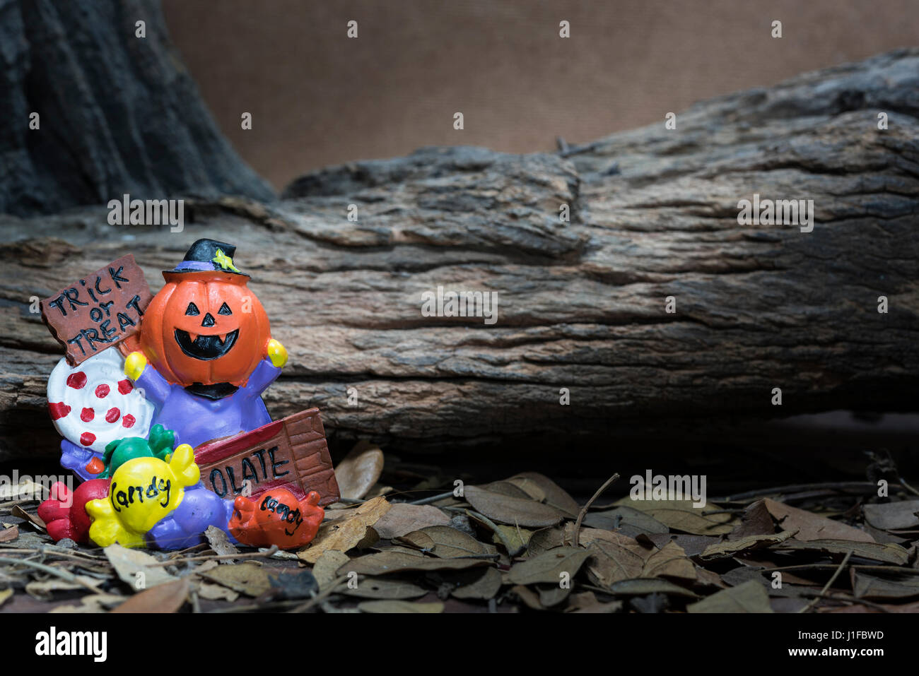 Pumpkin head jack with trick or treat board and candy over forest