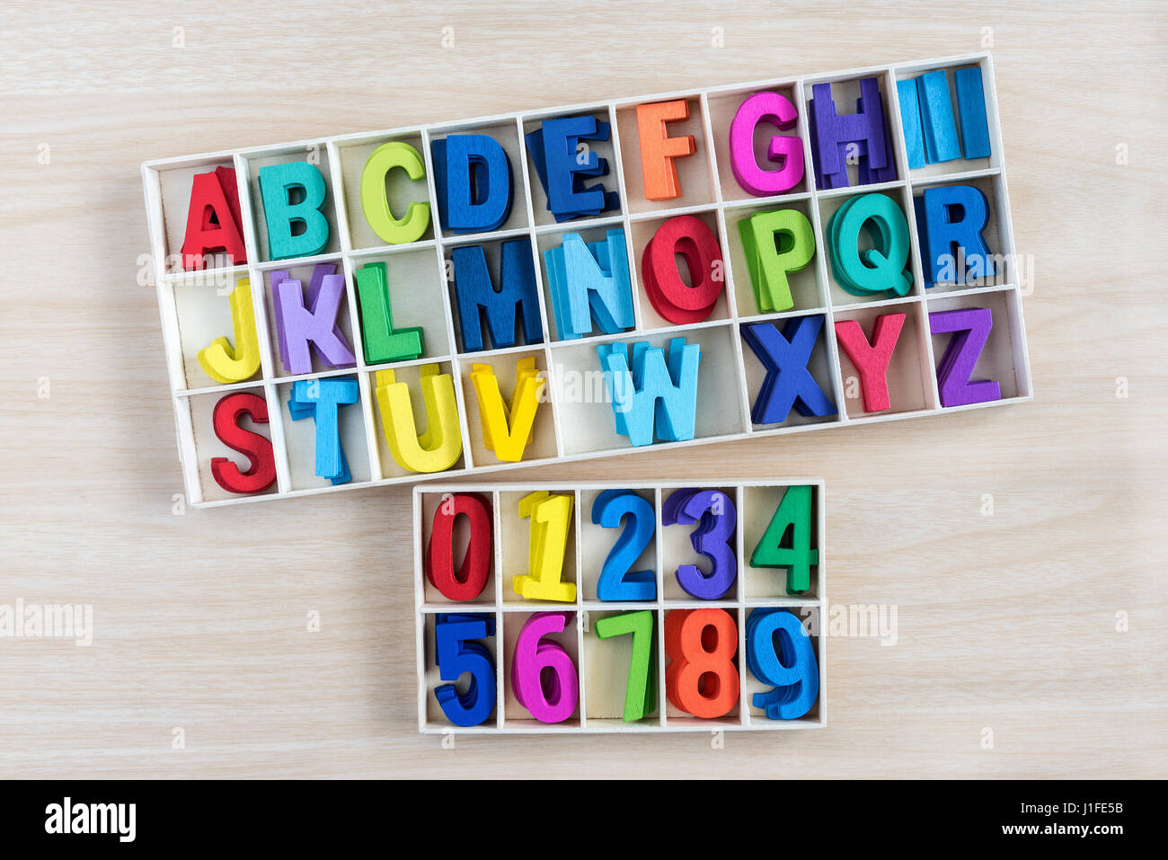 colorful alphabet letters and number in a wooden box with square compartments for teaching kids to read and spell, overhead viewful Stock Photo