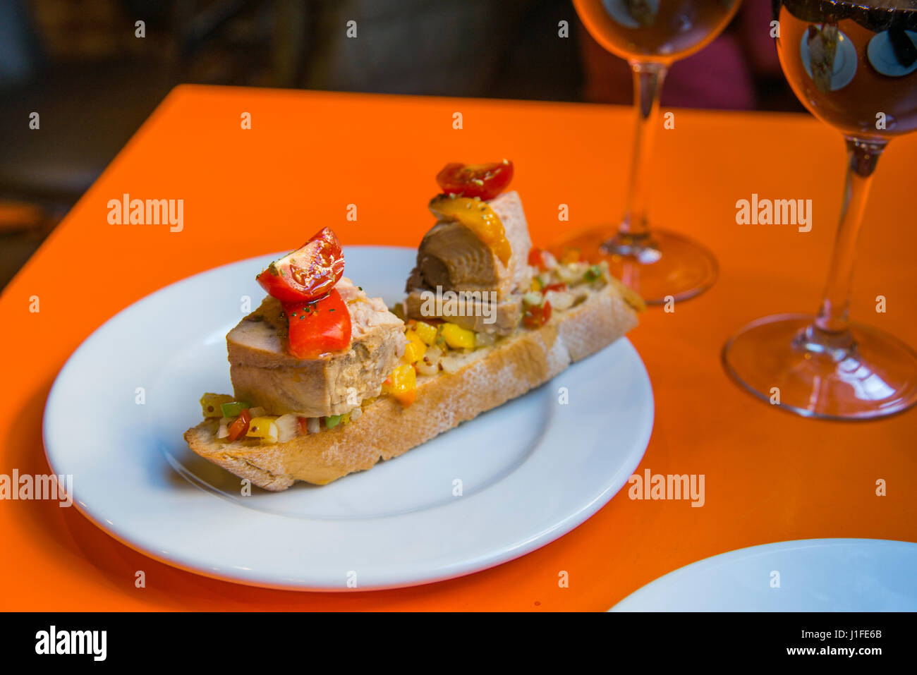 Spanish tapa made of tuna loin with peppers and cherry tomatoes on toast. Spain. Stock Photo