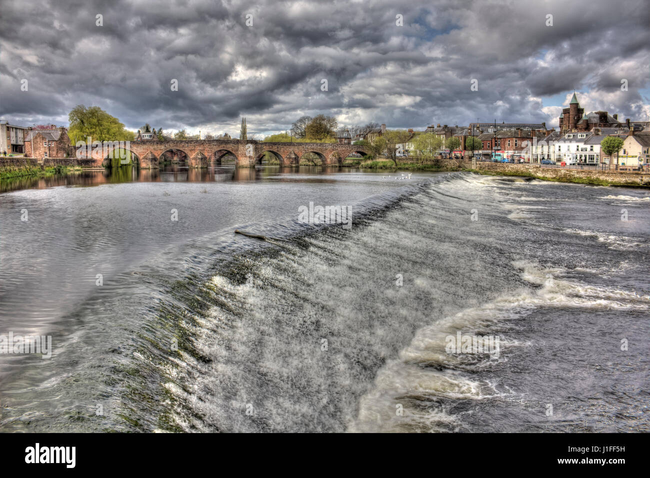 HIgh Dynamic Range image of Devorgilla Bridge and The Caul (local name for the weir), Dumfries. The turrets of the Sherriff Court are visible in back. Stock Photo
