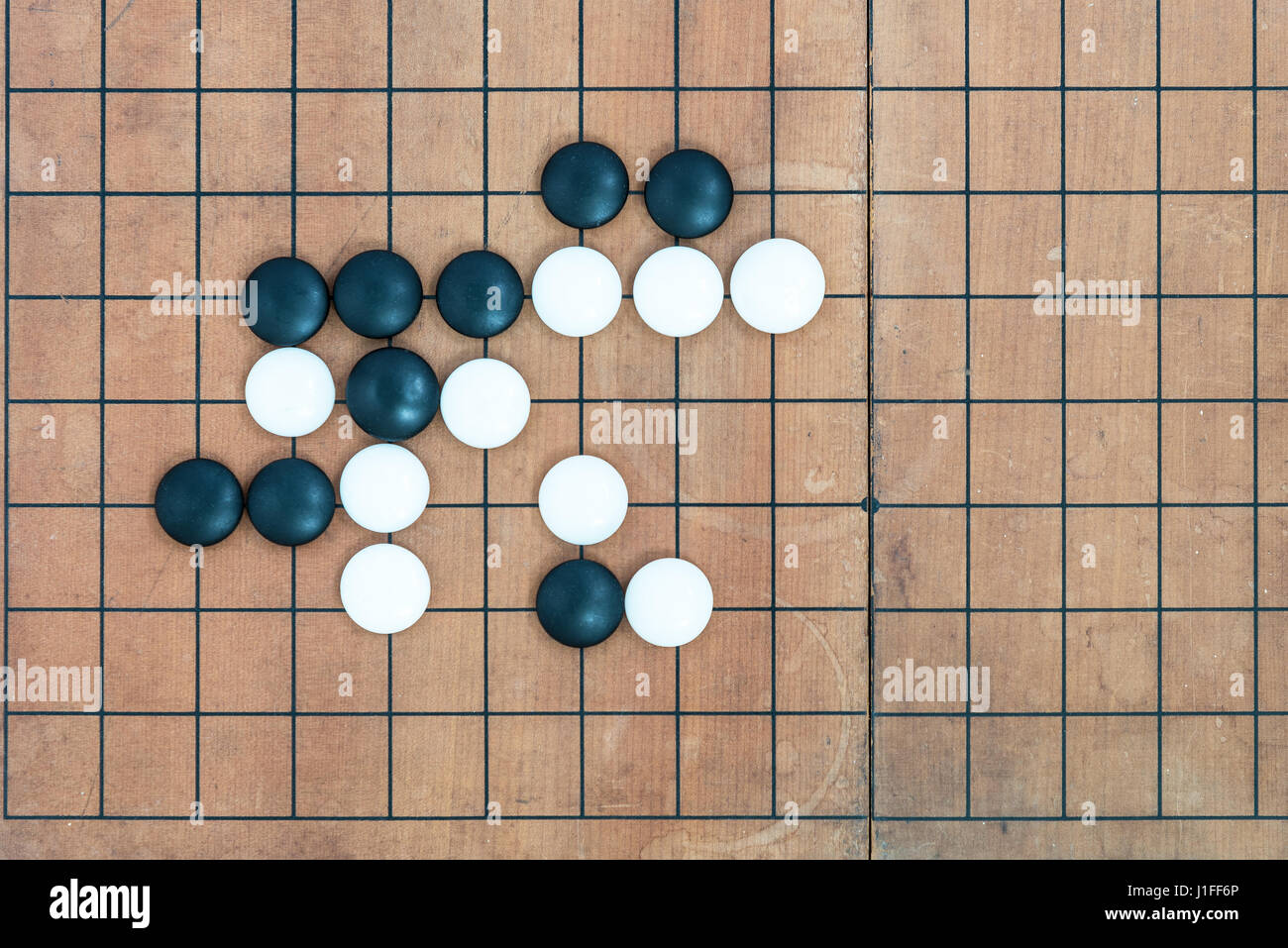 top view black and white stones playing with basic joseki in conner on go game board