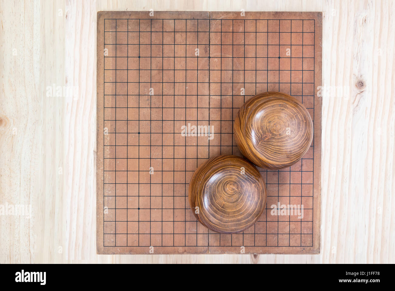 top view two wooden bowls filled black and white stones over empty go ...