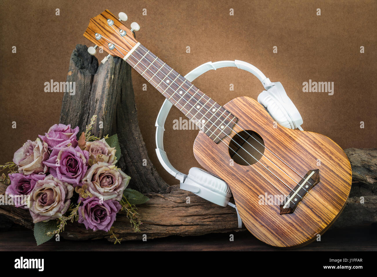 still life photography with ukulele and headphone on flower background