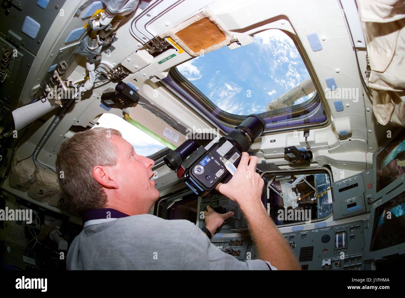 Photoelectric Maladroit Comrade NASA STS-82 prime crew astronaut Steve Hawley uses a 70mm Hasselblad camera  to photograph the Hubble Space Telescope from the overhead flight deck  windows aboard the Space Shuttle Discovery February 14, 1997