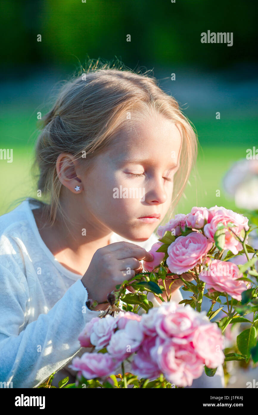 Little adorable girl smelling colorful flowers outdoor Stock Photo - Alamy