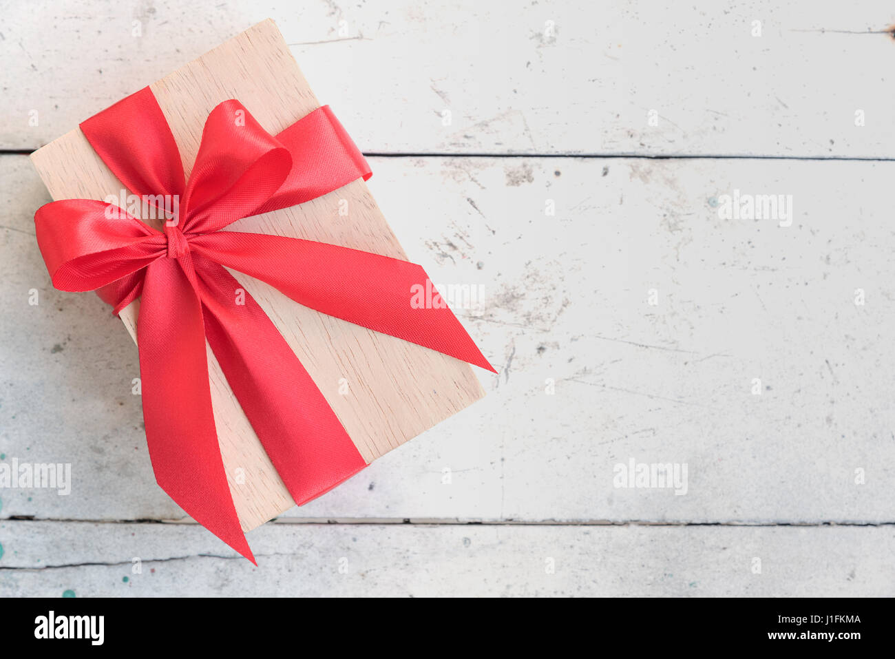 wooden gift box with shiny red satin ribbon bow on vintage background ...