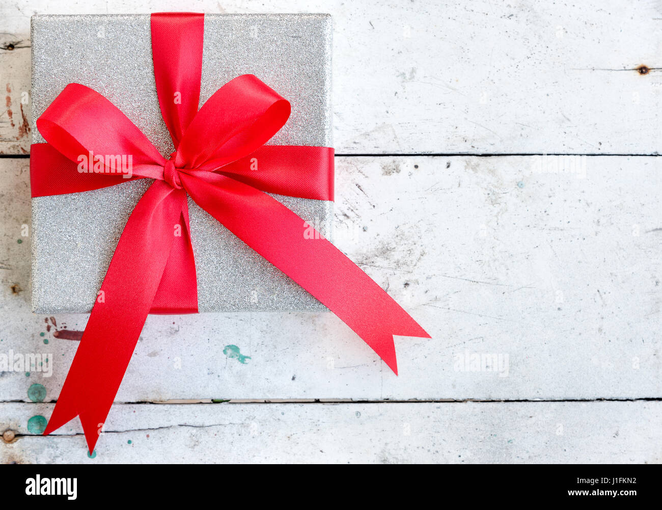silver gift box with shiny red satin ribbon bow on vintage background ...