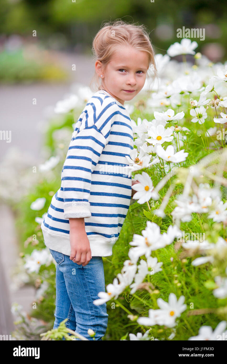 Little adorable girl smelling colorful flowers outdoors Stock Photo - Alamy