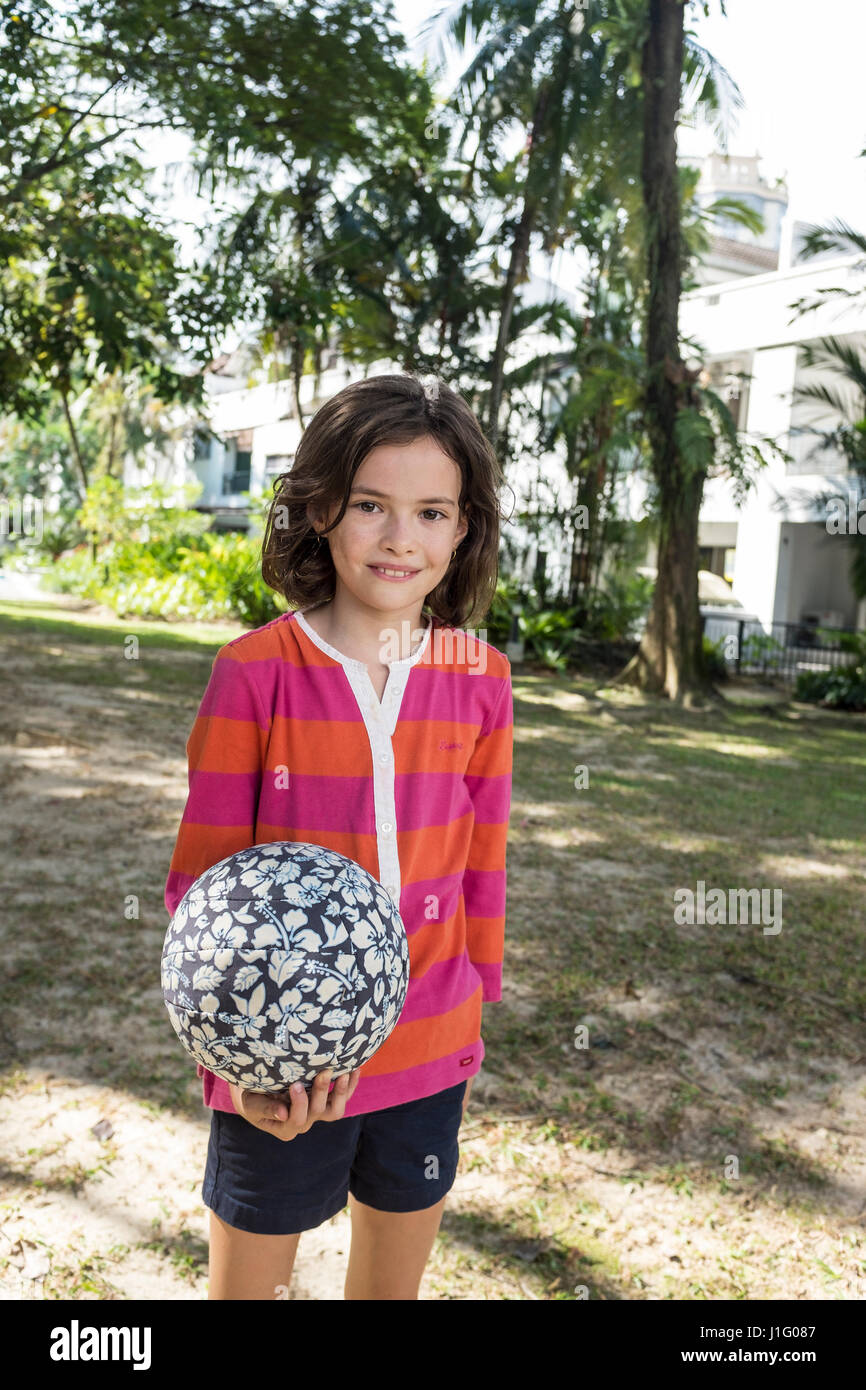 A 10 year old girl holds a football in a small park Stock Photo