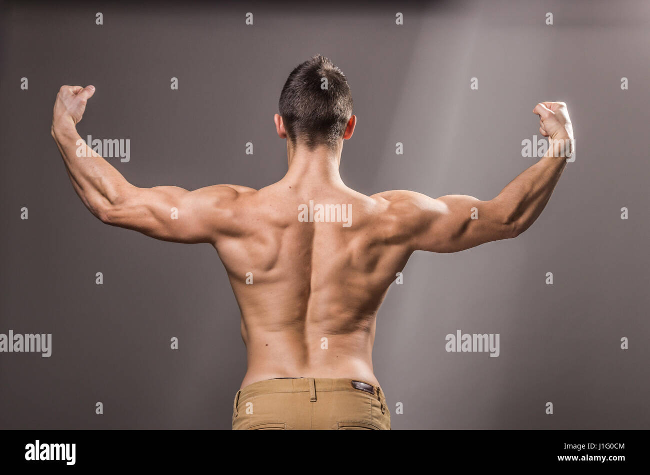 rear view, back muscles bodybuilder, young adult man posing, arms hands