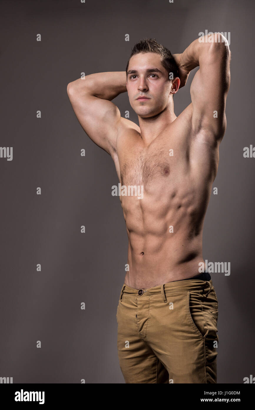 young bodybuilder posing strong muscular torso, chest, abs, arms up
