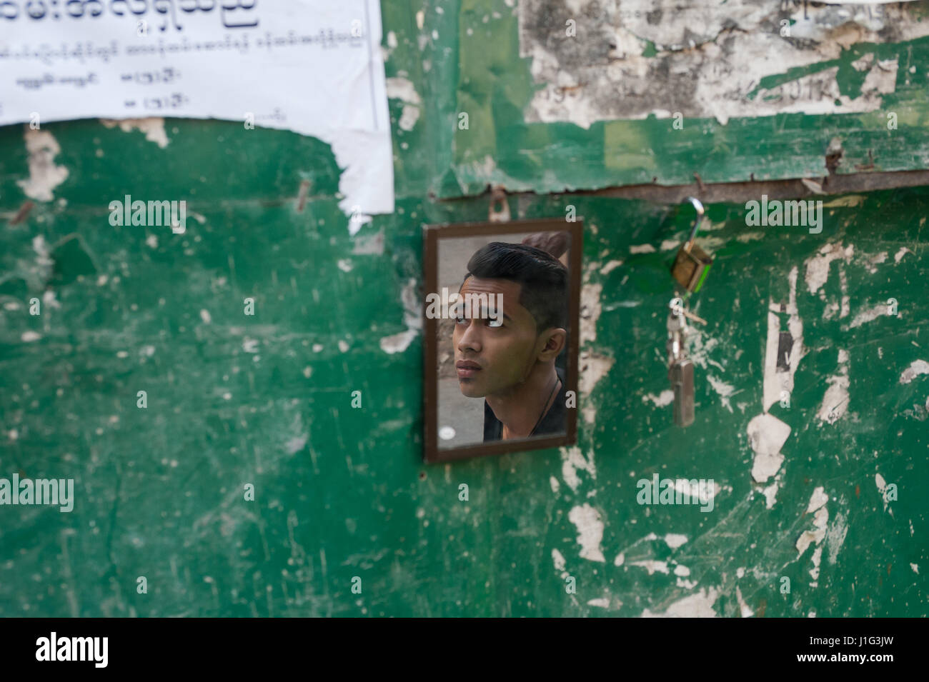 28.01.2017, Yangon, Republic of the Union of Myanmar, Asia - The face of a young man is reflected in a small mirror at the roadside. Stock Photo