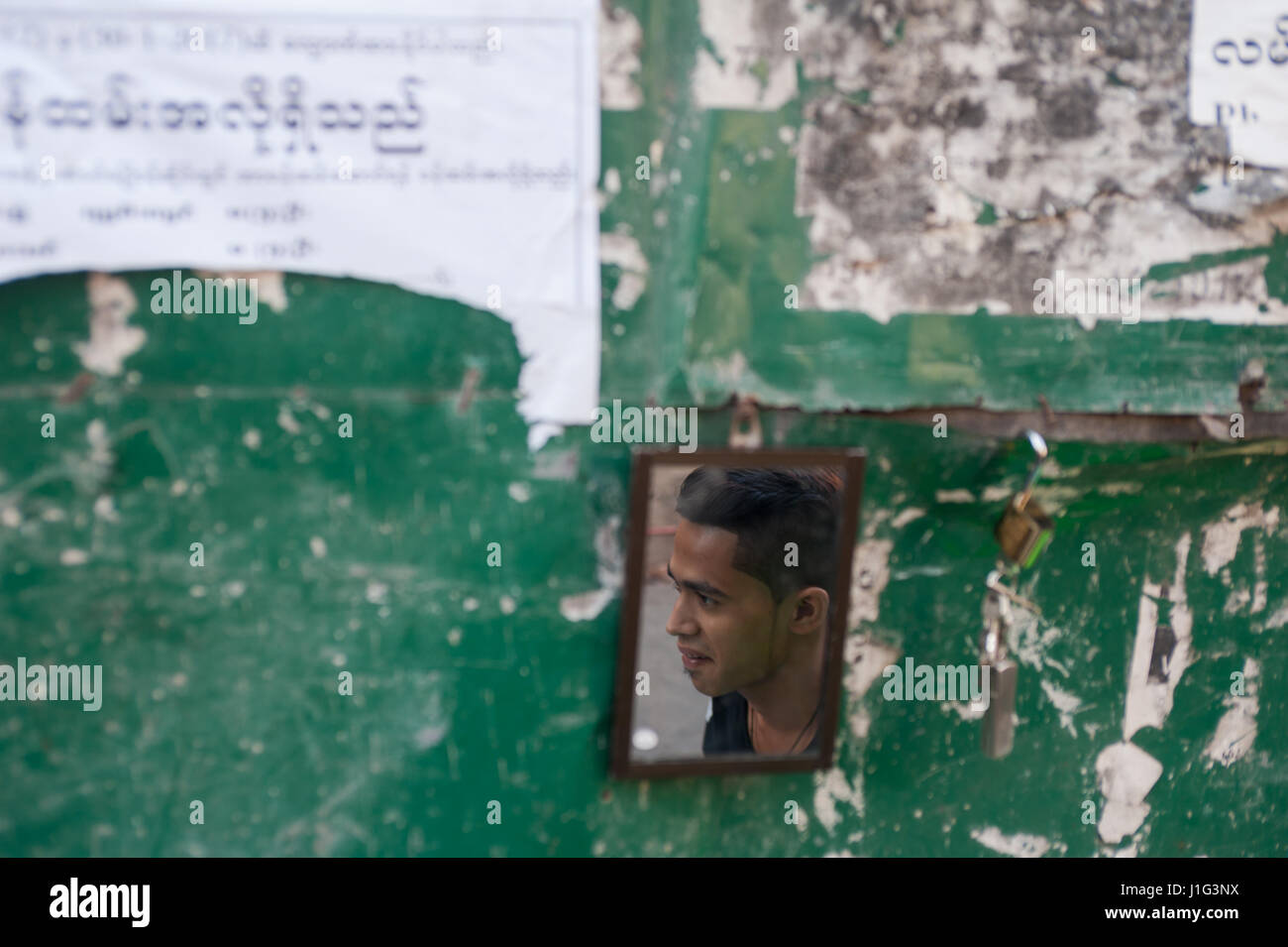 28.01.2017, Yangon, Republic of the Union of Myanmar, Asia - The face of a young man is reflected in a small mirror at the roadside. Stock Photo