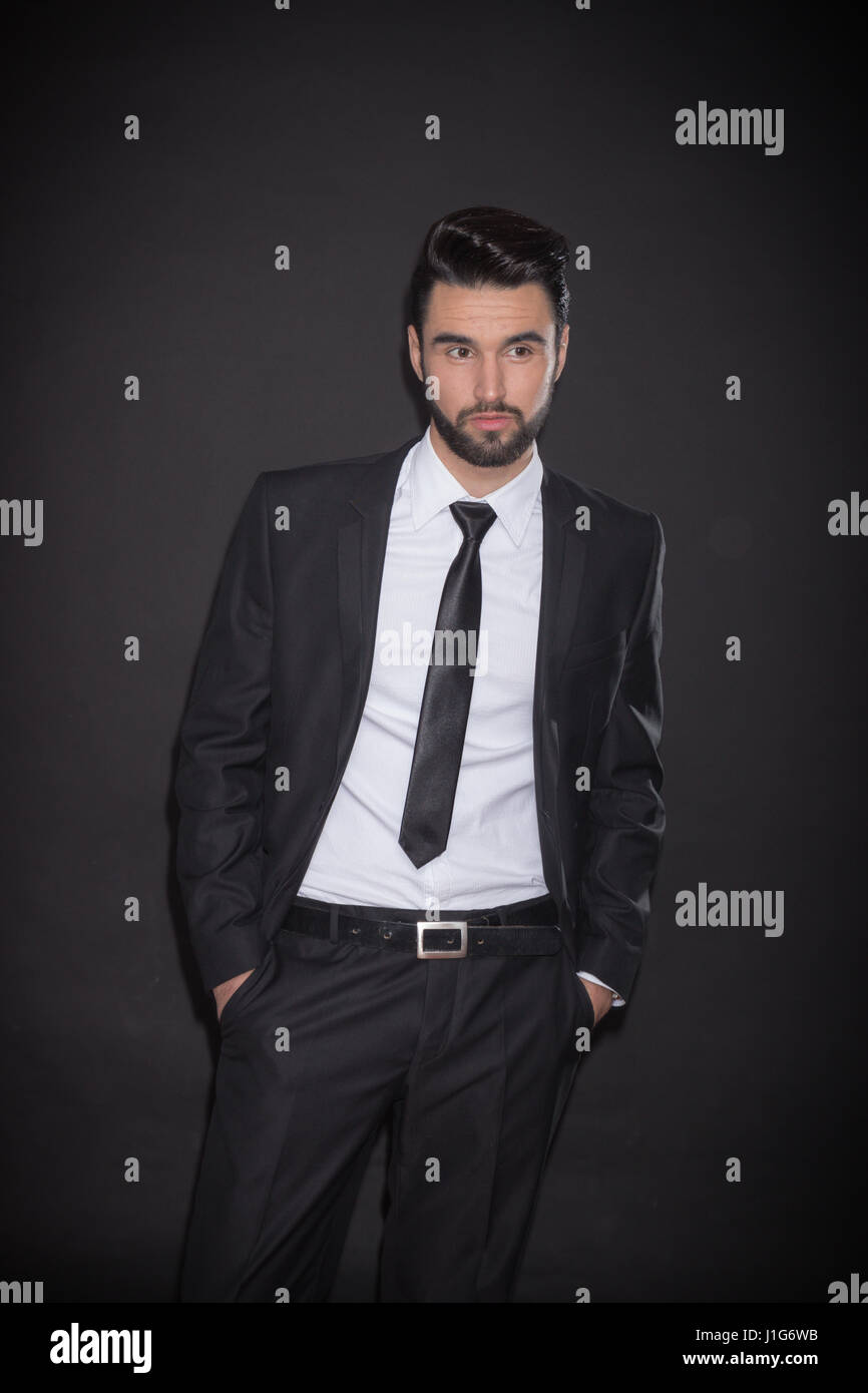 one young man handsome suit elegant shirt jacket tie pants, looking sideways, black background Stock Photo