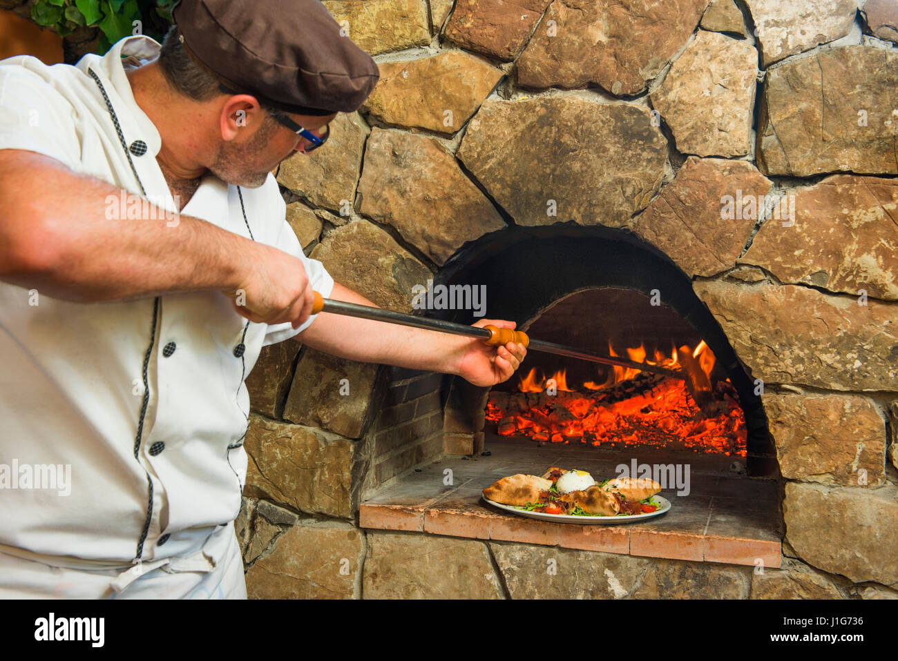 The cook sliding out pizza from a oven. Stock Photo
