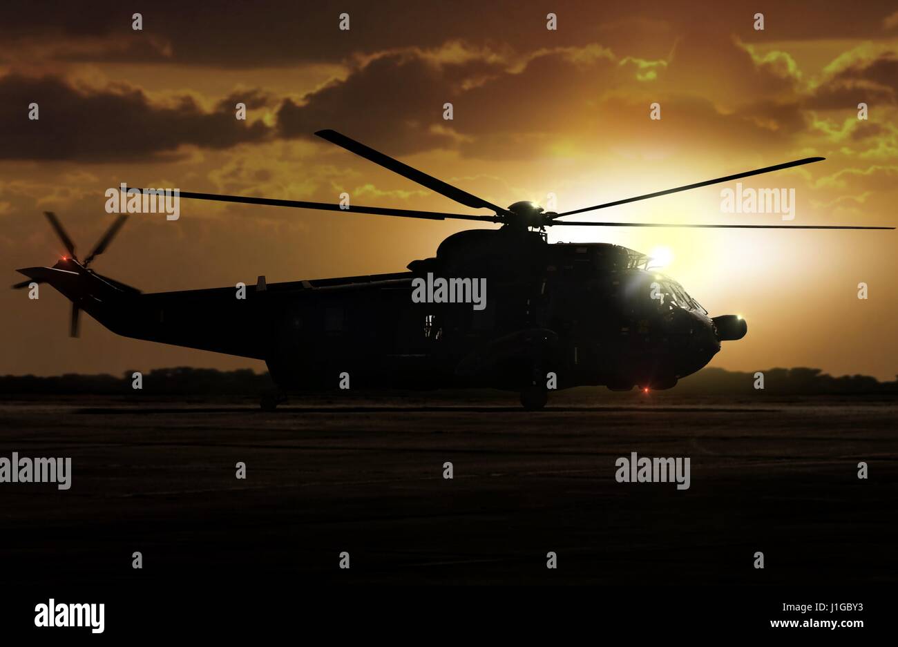 Military helicopter on airfield during sunset Stock Photo