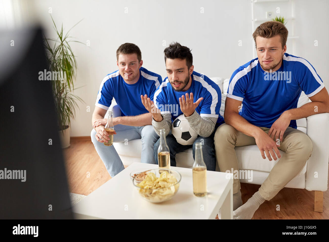 friends or football fans watching soccer at home Stock Photo