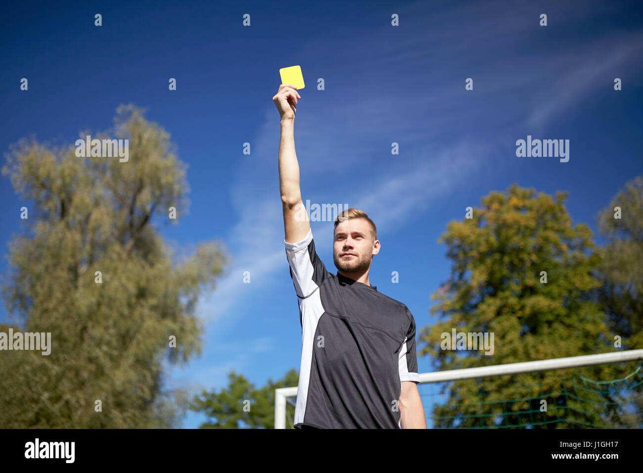 referee on football field showing yellow card Stock Photo
