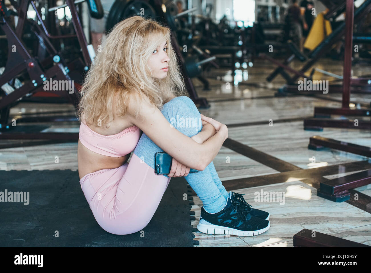 Girl sits on the floor in the gym Stock Photo - Alamy