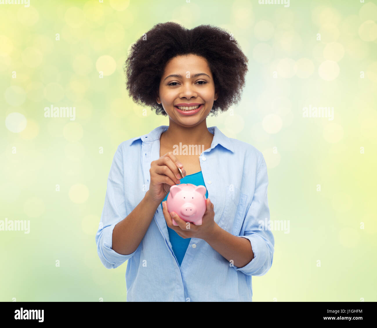 happy african woman putting coin into piggy bank Stock Photo - Alamy