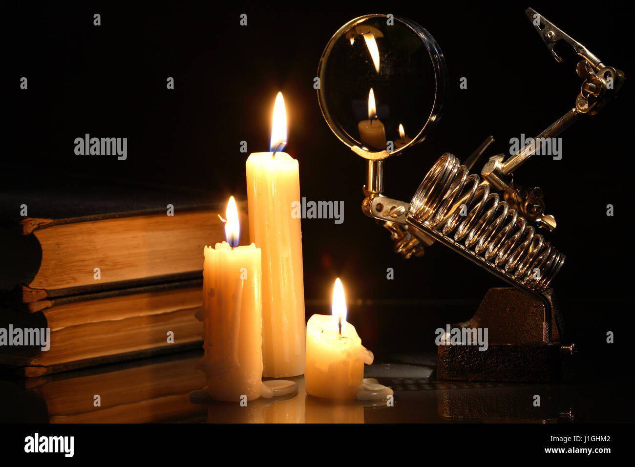 Science concept. Retro laboratory equipment and books  near lighting candles on dark background Stock Photo