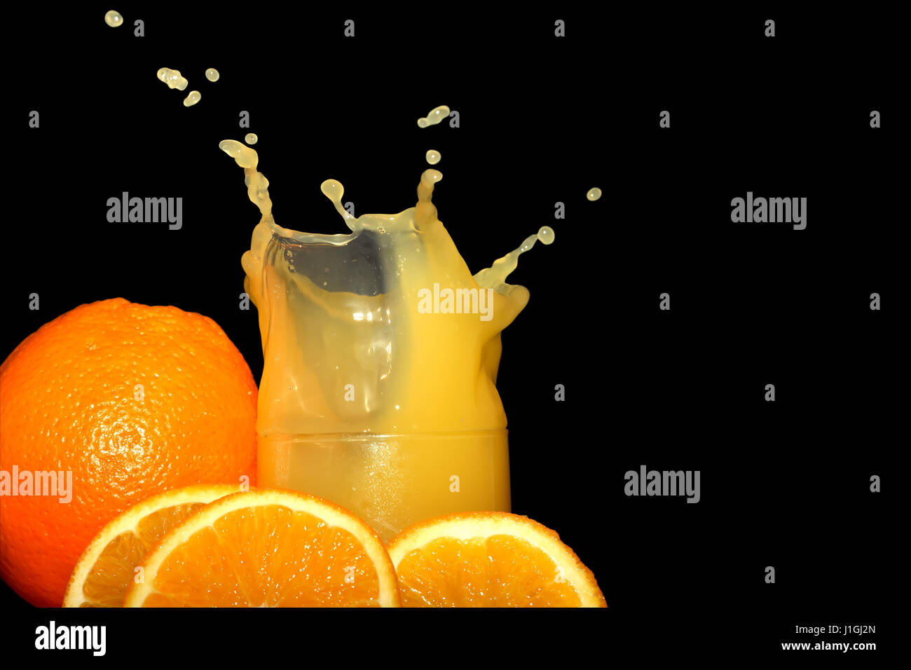 Glass of splashing orange juice on black background Stock Photo - Alamy