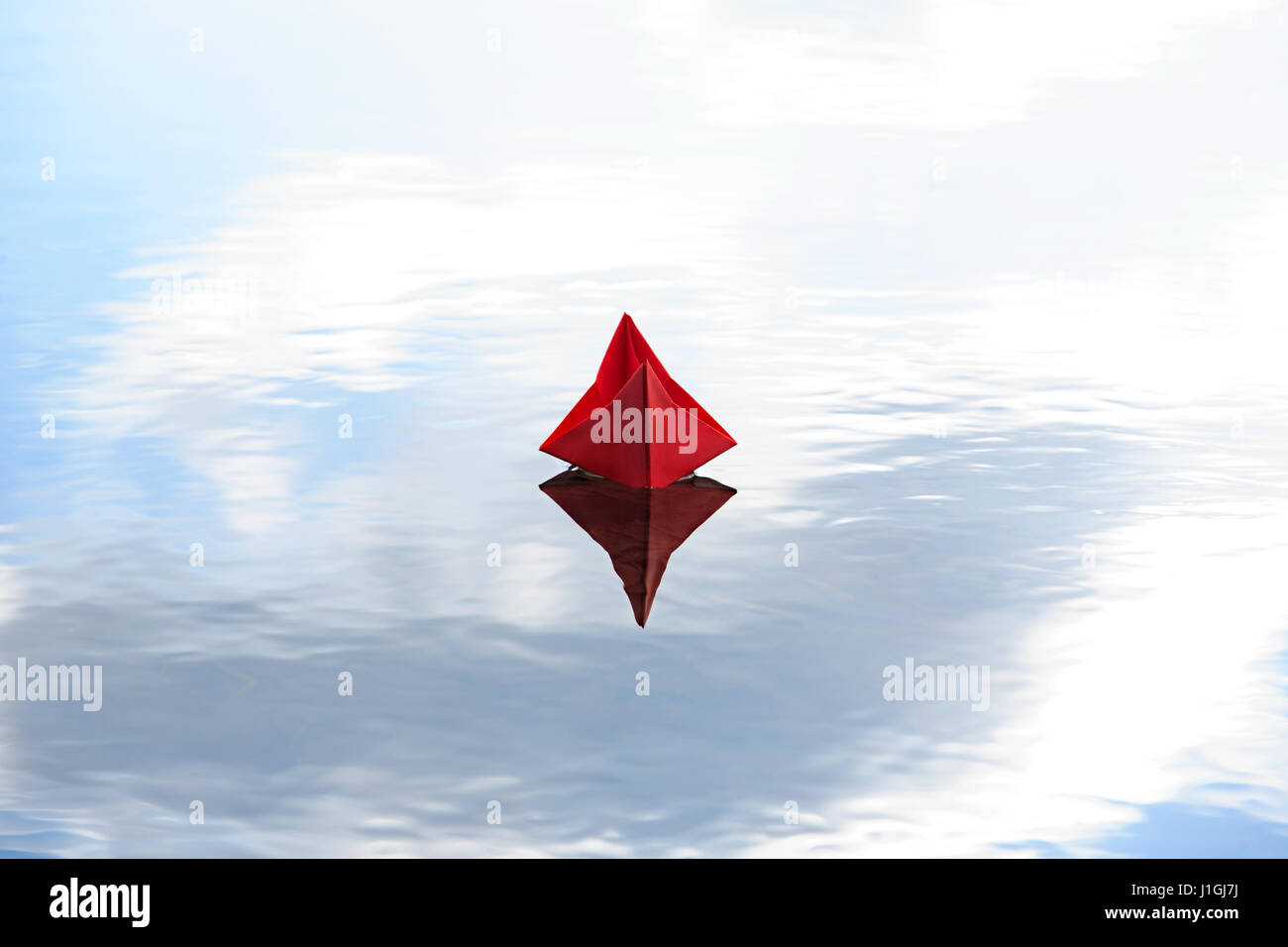 Red paper boat on blue water with free space for text Stock Photo
