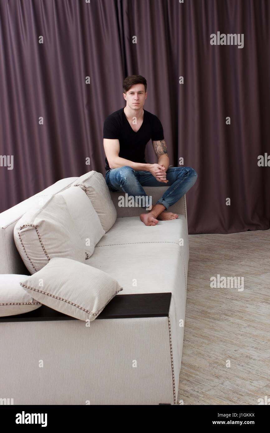 Portrait of a casual tired man resting sitting on a couch at home Stock Photo