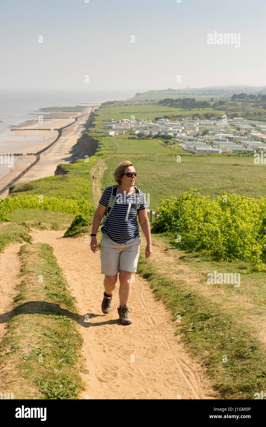 A woman walking up Beeston Hill, or Beeston Bump or Beeston Hump Norfolk UK on a sunny spring day Stock Photo