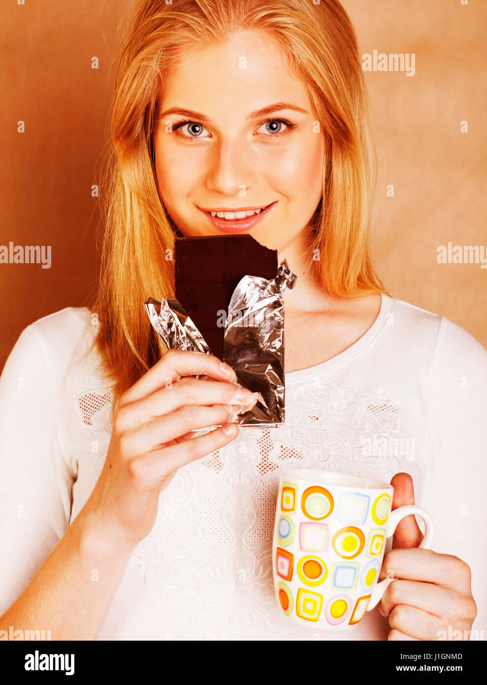 young cute blond girl eating chocolate and drinking coffee close Stock