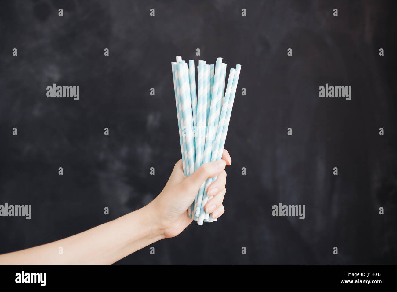 Woman hand hold cocktail straw on black background. Stock Photo