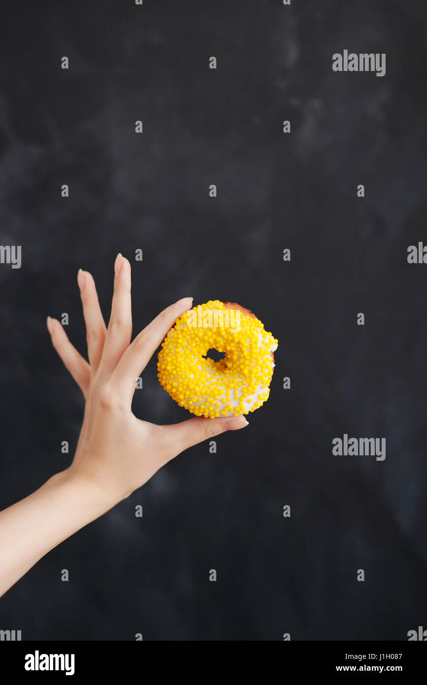 Yellow strip donut in a woman's hand Stock Photo