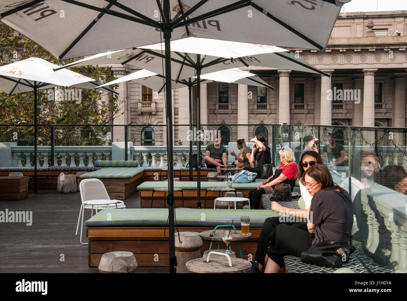 Patrons at a rooftop bar overlooking the Victorian Parliament on Spring Street, Melbourne, Australia Stock Photo