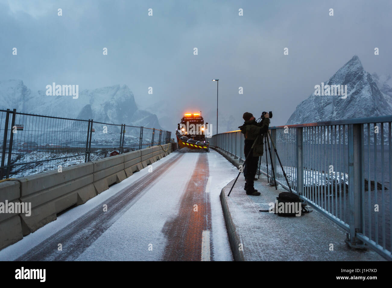 Hamnoy, Norway - March 16 2017: The snow-removing machine on the bridge with photographer on the foreground in snowstorm Stock Photo