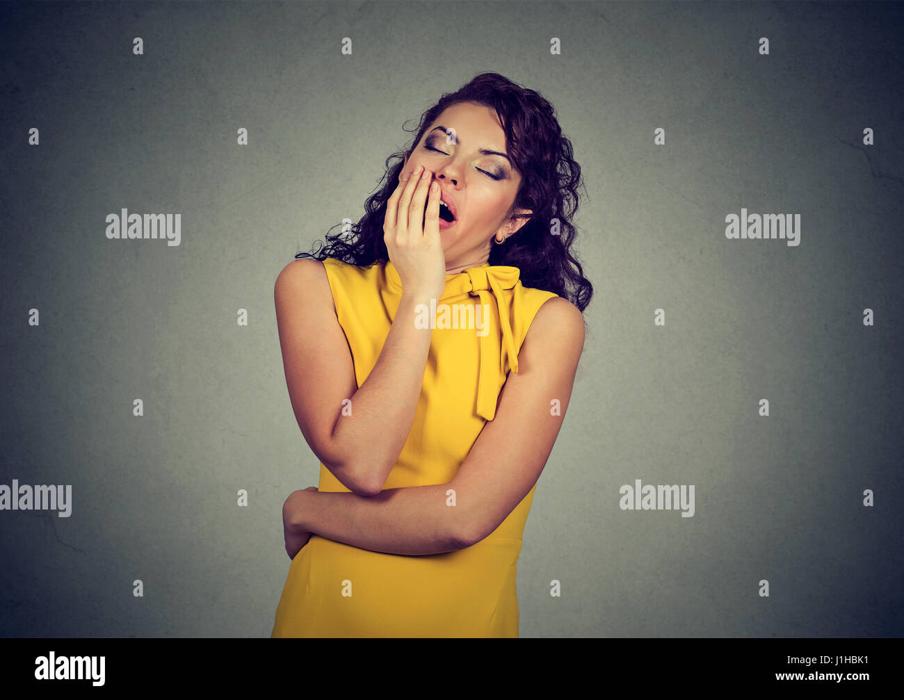 sleepy woman with wide open mouth yawning eyes closed looking bored isolated on gray wall background. Human face expression emotion Stock Photo