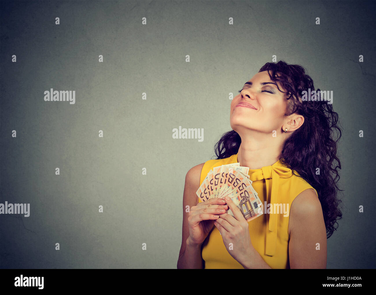 happy woman holding money isolated on gray background Stock Photo - Alamy