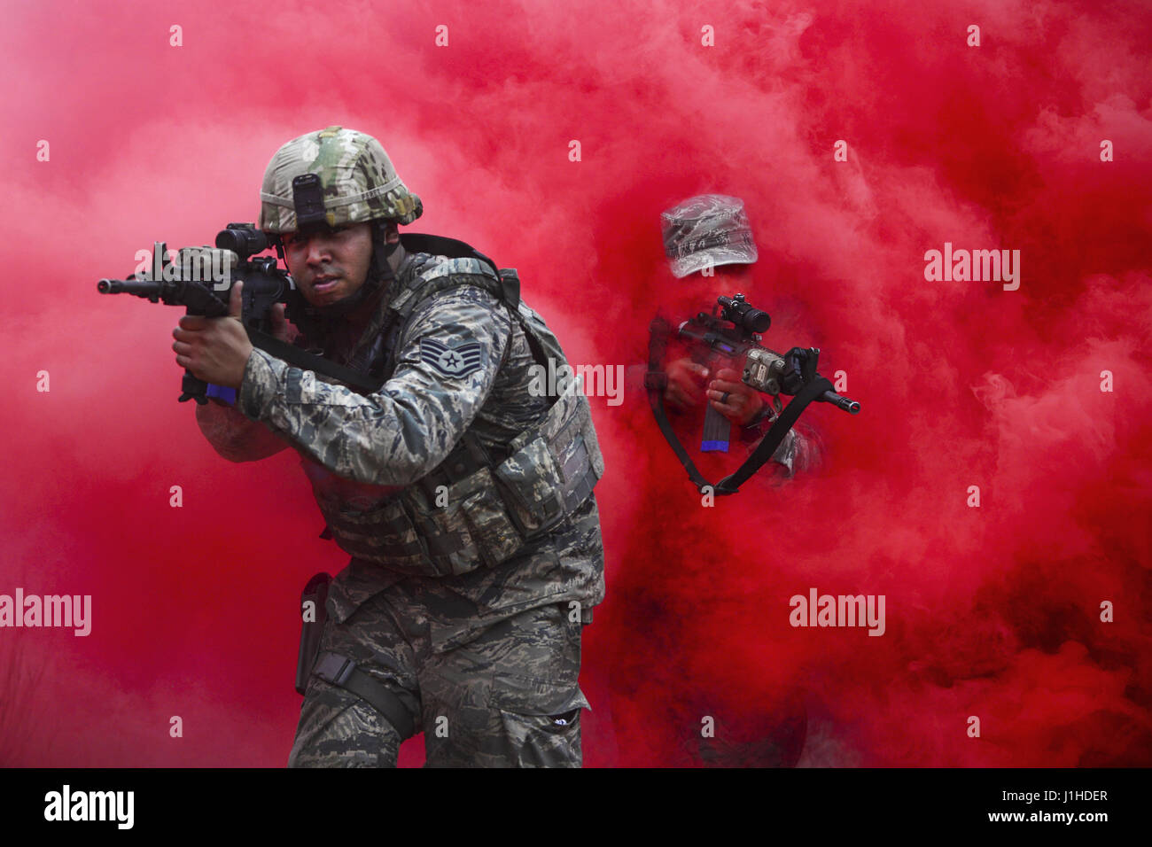 Airmen maneuver through concealing smoke during tactical combat training Stock Photo