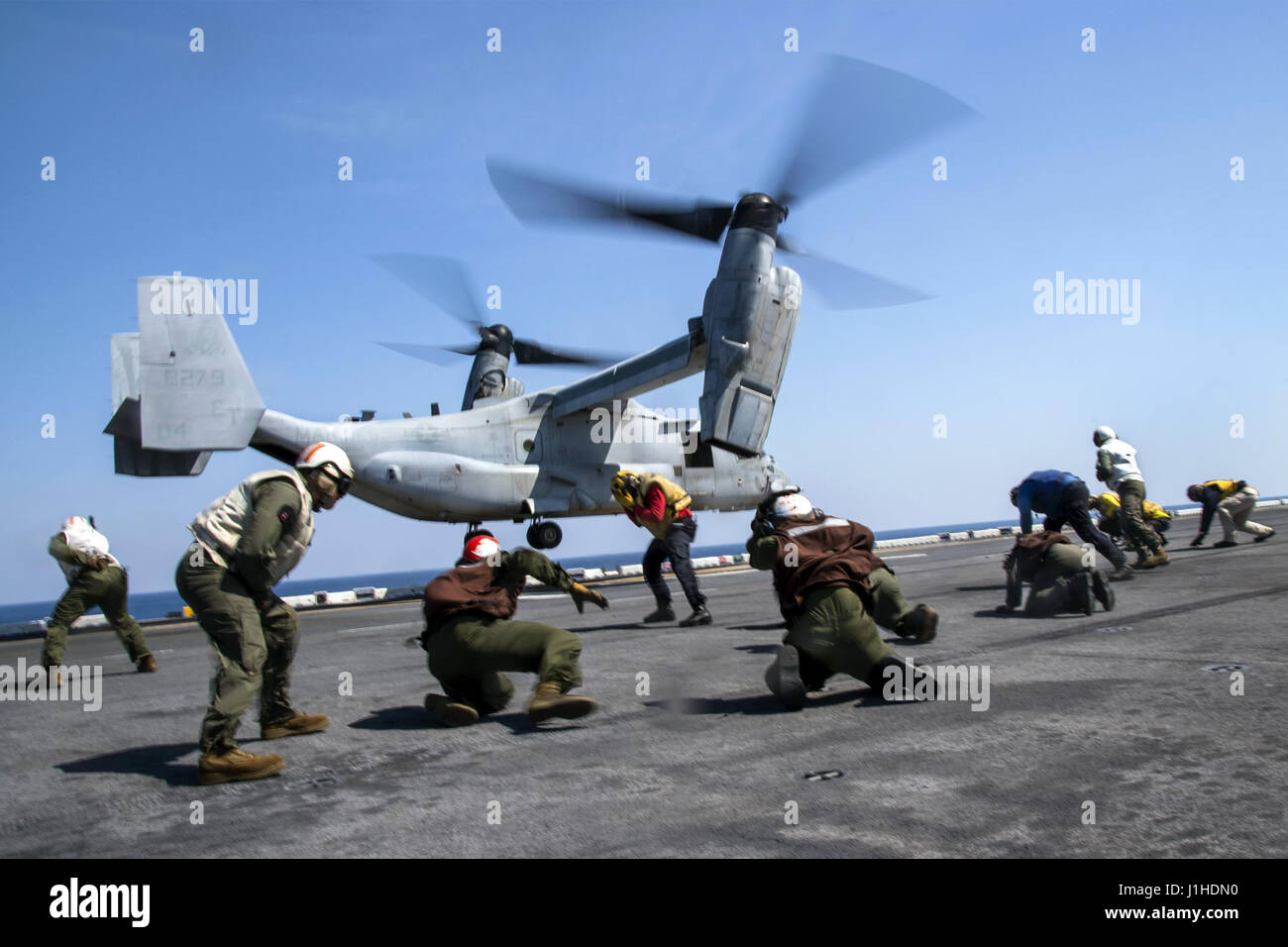 Sailors and Marines brace against rotor wash as an MV-22B Osprey Stock Photo